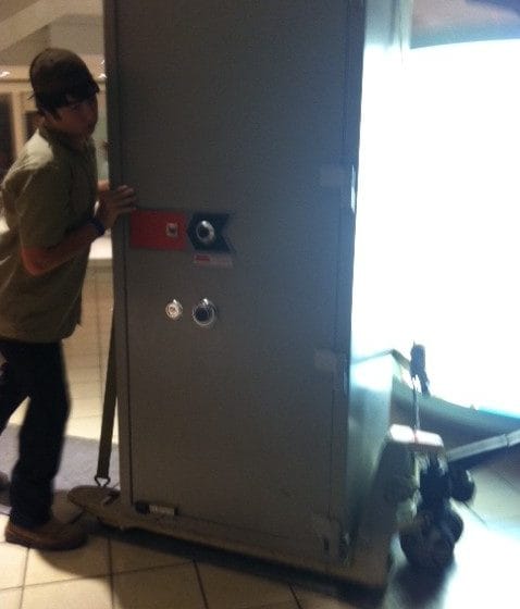 An extremely heavy jeweler's safe on the pallet jack rolling over runners and aluminum plates across a mall