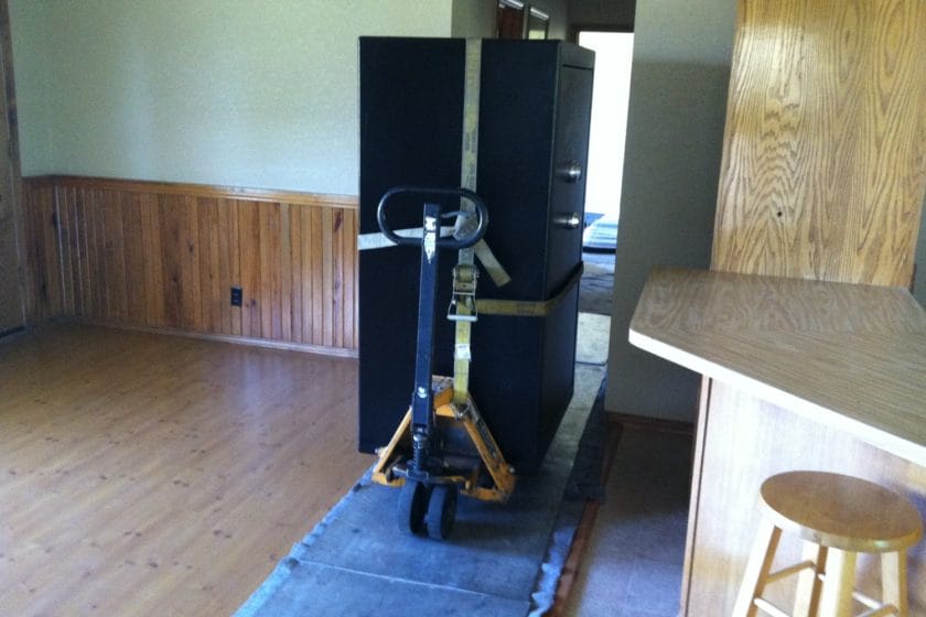 Liberty gun safe being moved on a pallet jack over blankets and aluminum plates through a house 2