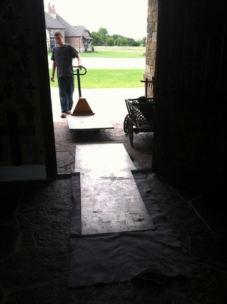 a safe mover making a ramp by placing aluminum plates and blankets over the threshold at the front door