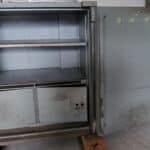 signal-2026-05-19-19-29-06-285 – The Safe Pros Large rusted metal safe with an open inner compartment on a wooden pallet in a dusty industrial space behind it tucked up against a wall