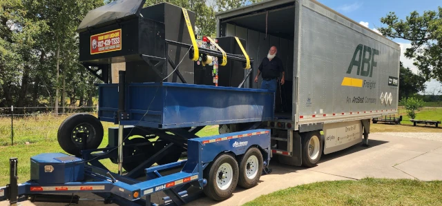 Our safe moving trailer backed up to a tractor trailer and raised up so we can load three gun safes into it.
